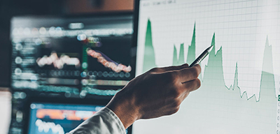 Close-up of young businessman pointing on the data presented in the chart with pen while working in creative office